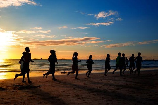 group of young people runs at the beach on beautiful summer